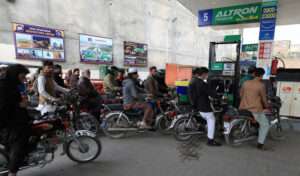 FILE PHOTO: People wait for their turn to get fuel at a petrol station in Peshawar