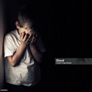 Depressed 6 years old child crying. Dark background.