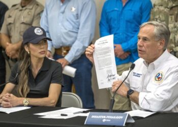 Texas Gov. Greg Abbott signs and holds up an disaster declaration proclamation as Homeland Security Secretary Kristi Noem,