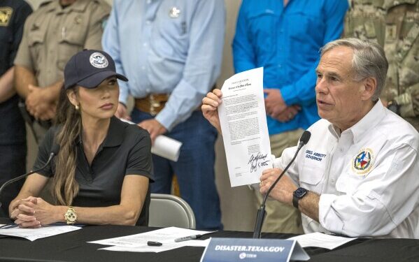 Texas Gov. Greg Abbott signs and holds up an disaster declaration proclamation as Homeland Security Secretary Kristi Noem,