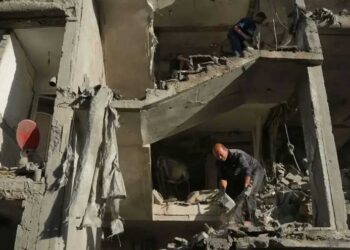 Damaged buildings in Gaza after Israeli airstrikes with emergency responders at the scene.