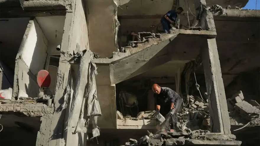 Damaged buildings in Gaza after Israeli airstrikes with emergency responders at the scene.