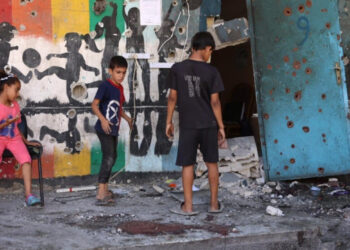 Destroyed buildings in Gaza with displaced families and children amid conflict aftermath