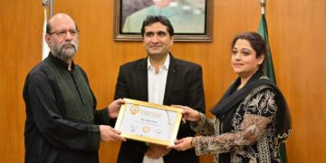 Senior Pakistani artist Aliya Faizi receiving a Certificate of Appreciation at the FPCCI Lifestyle Committee exhibition alongside organisers and guests.