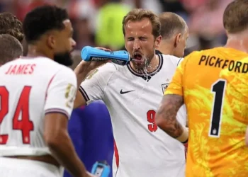 Football players pausing for hydration break during World Cup match in stadium under hot conditions