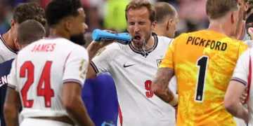 Football players pausing for hydration break during World Cup match in stadium under hot conditions