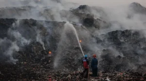 Firefighters working to extinguish the Jatiwaringin landfill fire near Jakarta as thick smoke covers the surrounding area.