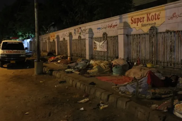 Police inspect the site where a pickup truck struck a homeless man and injured his son in DHA Karachi.