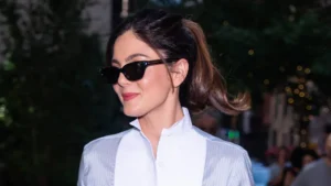 Monica Barbaro styling a blue-and-white tuxedo shirt with black tailored trousers and pumps