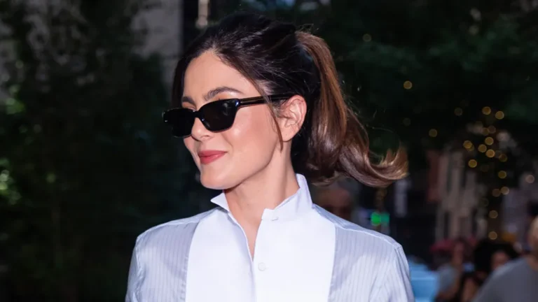 Monica Barbaro styling a blue-and-white tuxedo shirt with black tailored trousers and pumps