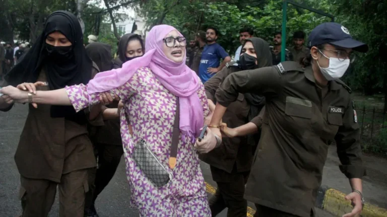 Journalists report outside a government building as Pakistan introduces new foreign media reporting restrictions.