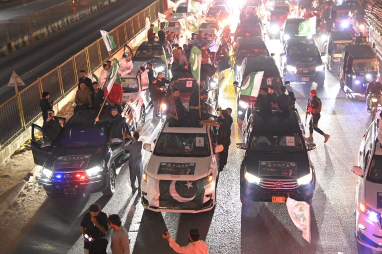Defence Day rally participants wave Pakistani flags during a gathering in Karachi.