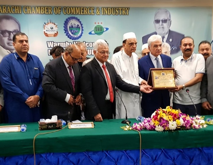 Ilyas Memon receives an honorary shield from KCCI President Talat Mahmood at a ceremony recognising his services to Tariq Road traders.